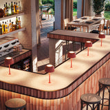 Bol M/33 Dome LED Table Lamp in Textured Terracotta, dome shade on slim stem with round base, shown lit on an outdoor bar counter among matching lamps.