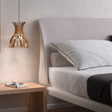 Domita S/20 bell-shaped wood pendant light with curved natural wood slats forming an open lattice, hung beside a bed with beige upholstered headboard.