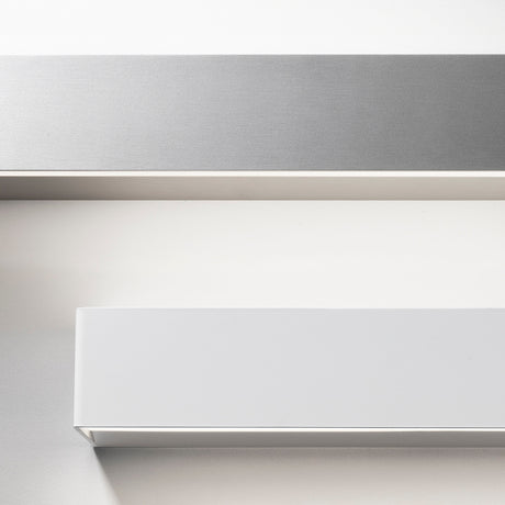Close-up of the Toy S LED Wall Light 57.7cm in White, a slim rectangular bar with crisp corners and a flat face, shown above a brushed metal bar on a plain light background.