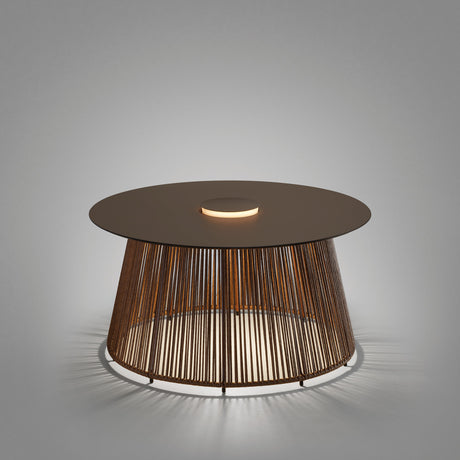 Nit/80/R rechargeable outdoor table lamp with round stone-brown top, woven synthetic fibre drum base, and integrated LED ring glowing through the cords, shown on a plain grey background.