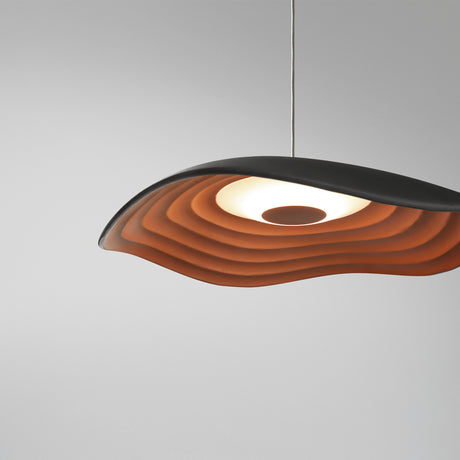 Valentina S/24 LED pendant light with wavy leaf-shaped shade, smooth black top and tiered copper underside, aluminium and iron structure, on a plain grey background.