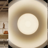 Close-up of the Bug Halo recessed LED downlight in Brushed Titanium, showing its deep round reflector glowing warm white inside a silver-grey finish, with a dim retail interior visible alongside.