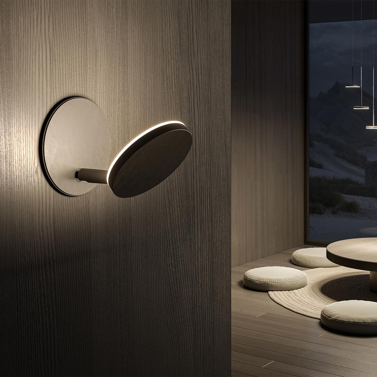 Bella Direct Aluminium Recessed LED Wall Light in bronze, round plate with angled disc head on a short stem, shown illuminated on a wood-panelled wall in a dimly lit lounge setting.