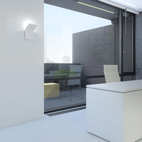 App Aluminium LED Wall Light in white, its curved panel mounted on an office wall near a glass sliding door, desk and chair visible in the room.