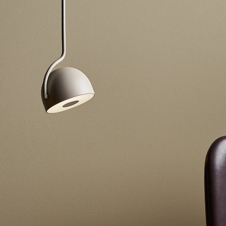 Bowee S1 Dome LED Pendant Light in beige, with a single dome shade on a slim bent stem, shown against a neutral wall beside a dark upholstered chair.
