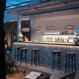 Perris S/47 Outrack LED outdoor track pendant lights with woven brown globe shades hanging above a stone bar counter in an evening outdoor setting.