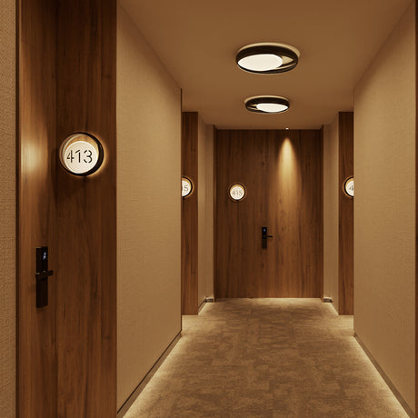 Ring W1 Number glass ring wall lights mounted outside hotel room doors in a wood-panelled corridor, round black frames with illuminated white number discs.