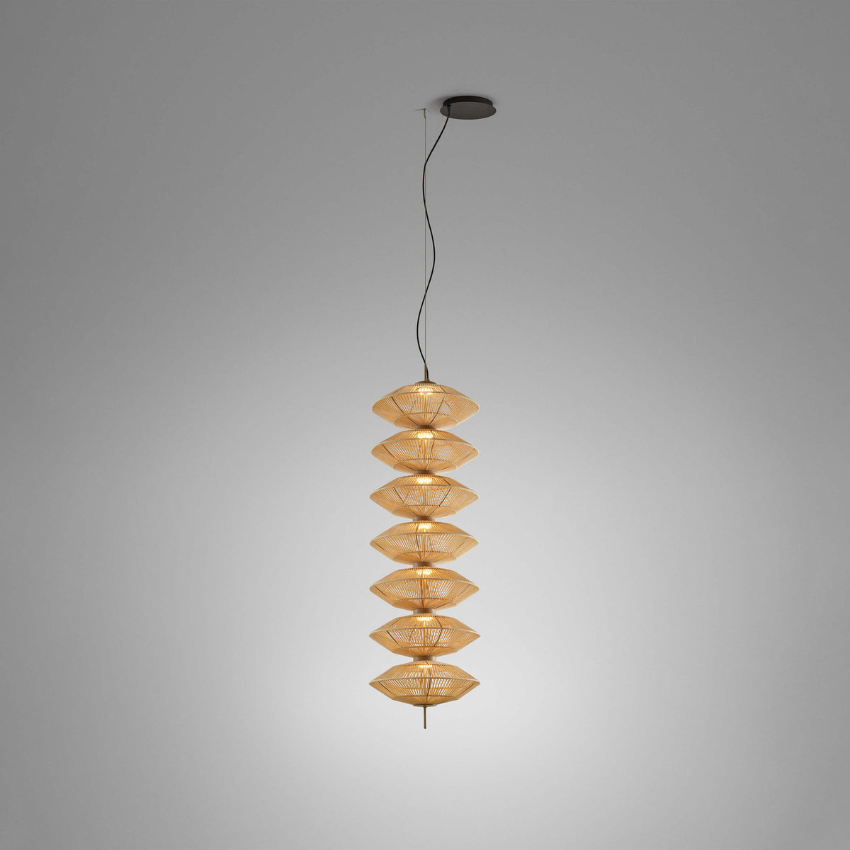 Yuyun S/7L fabric LED pendant light with seven stacked woven cotton tiers on a slim metal stem, satin beige finish, shown lit against a plain grey background.