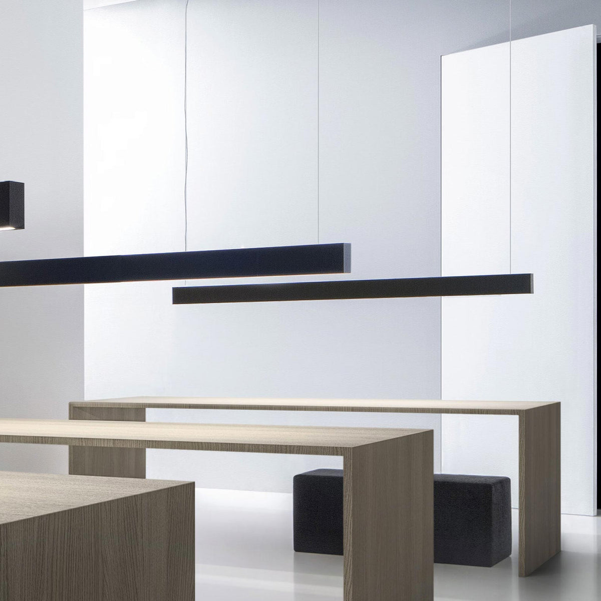 Giano Aluminium Linear LED Pendant Light in black, a slim squared bar suspended above wooden dining tables in a modern interior setting.
