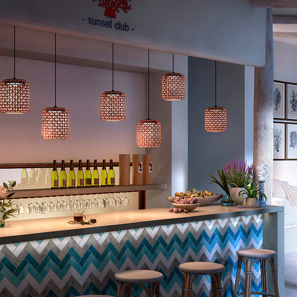 Nans S/21 LED outdoor pendant lights with woven red lattice cylindrical shades hanging above a bar counter with blue chevron tiling.