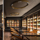 R2 C60 Aluminium Ring LED Ceiling Light in brass, two circular flush fittings with integrated LEDs, shown in a library lounge with bookshelves and seating.