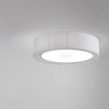 Urban PF/60 Ribbon LED ceiling light with a round drum shade in pleated white translucent ribbon, iron frame, and a broad white diffuser, shown against a plain grey background.