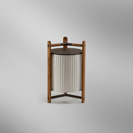 Kando M/40/R rechargeable LED table lamp with pleated white ribbon shade in a teak wood frame on three legs, flat round top, shown on a plain light background.