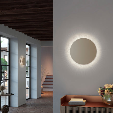 Helios A/02 round LED wall light with oak brown disc face and beige fabric thread edge, glowing warm white in a hallway and entryway setting.