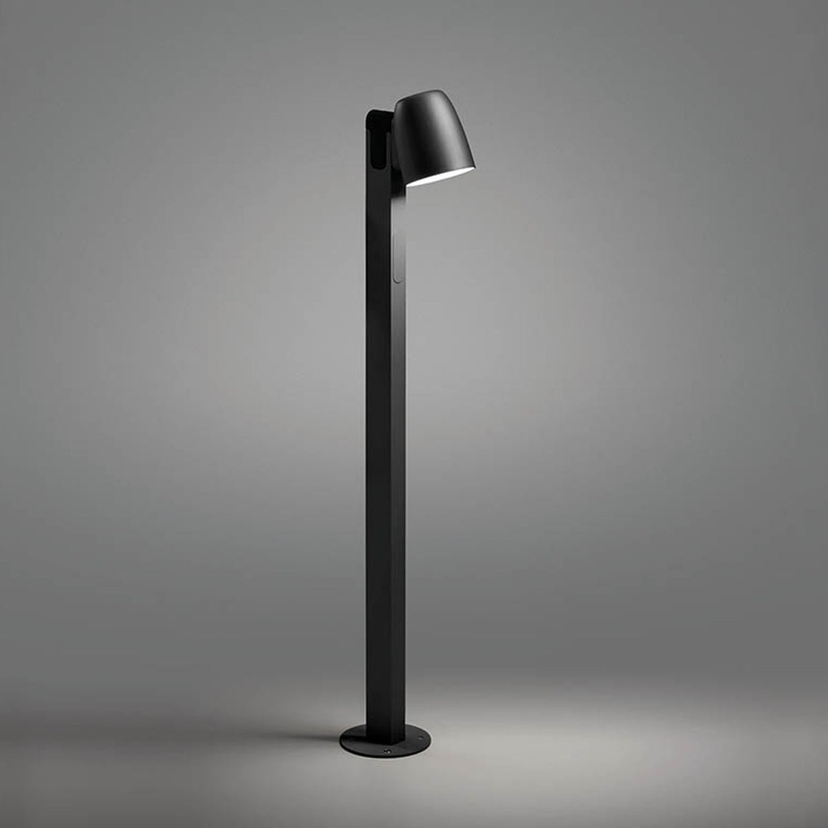 Nut B/90 Bell LED bollard light in textured black, with a bell-shaped head angled atop a slim square post and round base plate, shown against a plain grey background.