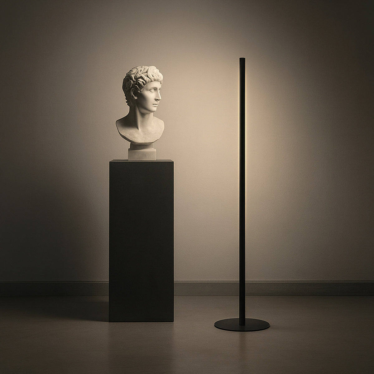 Solid F 240 Cylinder LED floor lamp with a slim black stem on a round disc base, glowing warm white beside a bust on a pedestal in a softly lit room.