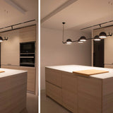 Bowee S4 4 Light Dome LED Pendant Light in matte black, four dome heads on a slim horizontal bar, shown above a kitchen island with wood cabinetry.