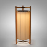 Kando P/111/R rechargeable floor lamp with a tall pleated cream ribbon shade in an open wooden frame, dark top disc, three slim legs, on a plain grey background.