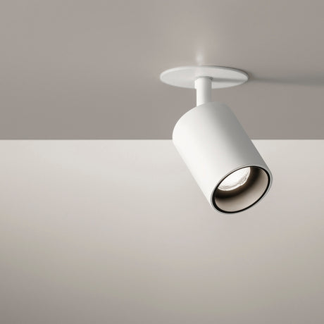 Carl Adjustable Recessed LED Downlight in white, with a cylindrical tiltable head on a short stem beneath a round ceiling trim, shown angled against a muted grey ceiling.