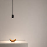 Anvil Spot SR 38° black aluminium LED pendant light with slim cylindrical head on a thin cord, casting a focused downward spotlight above a table in a neutral setting.