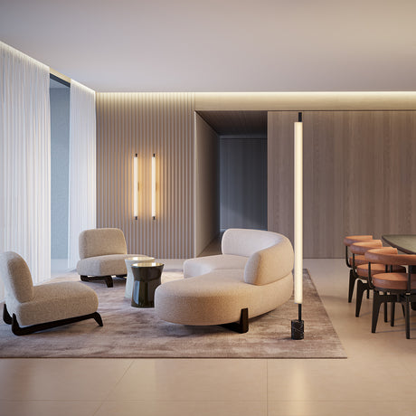 Ombra Nero Marquina LED floor lamp with tall cylindrical fabric shade, slim brushed brass stem and black marble base, shown beside a beige sofa in a living room.