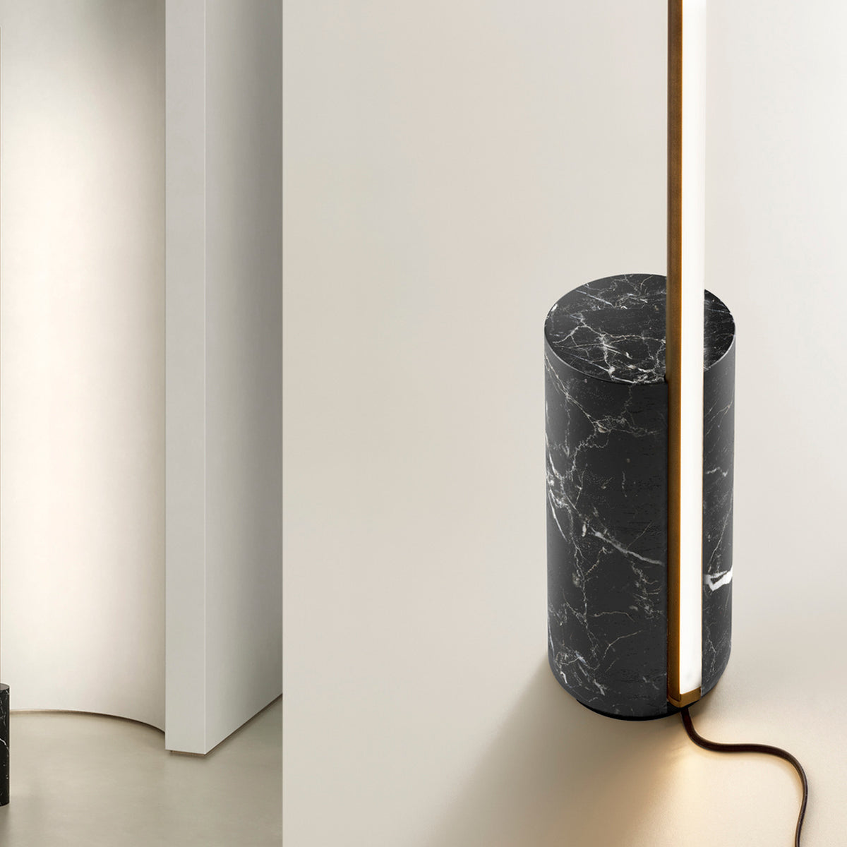 Hilow Line floor lamp with a slim Brushed Champagne aluminium rod rising from a cylindrical Nero Marquina marble base, shown against a neutral wall interior.