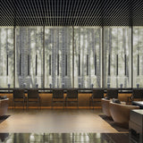 Multiple To-Be matt black aluminium linear LED pendant lights hang in a row above a lounge seating area with armchairs and a wood floor.
