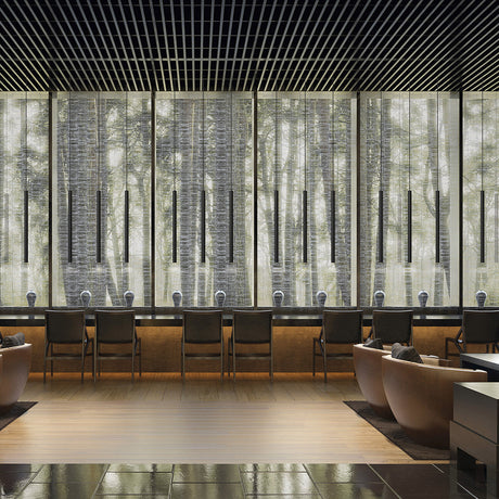 Multiple To-Be matt black aluminium linear LED pendant lights hang in a row above a lounge seating area with armchairs and a wood floor.