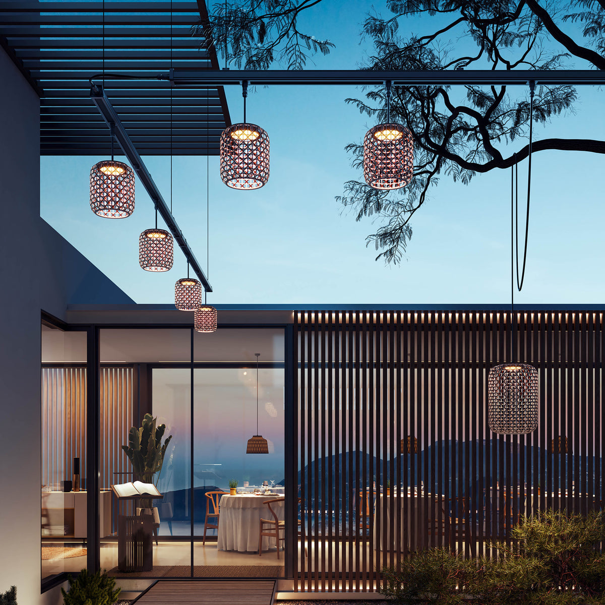 Nans S/16 Outrack woven LED outdoor track pendant lights with brown lattice barrel shades, suspended from a ceiling-mounted track above a modern patio at dusk.
