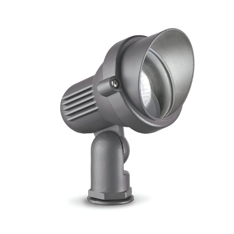 The Vespera Outside Small Single Spotlight in grey features a ribbed cylindrical design with an adjustable base, including a clear lens. Its weather-resistant construction has an IP65 rating for durability while presenting a sleek and modern appearance with its slightly upward angle.