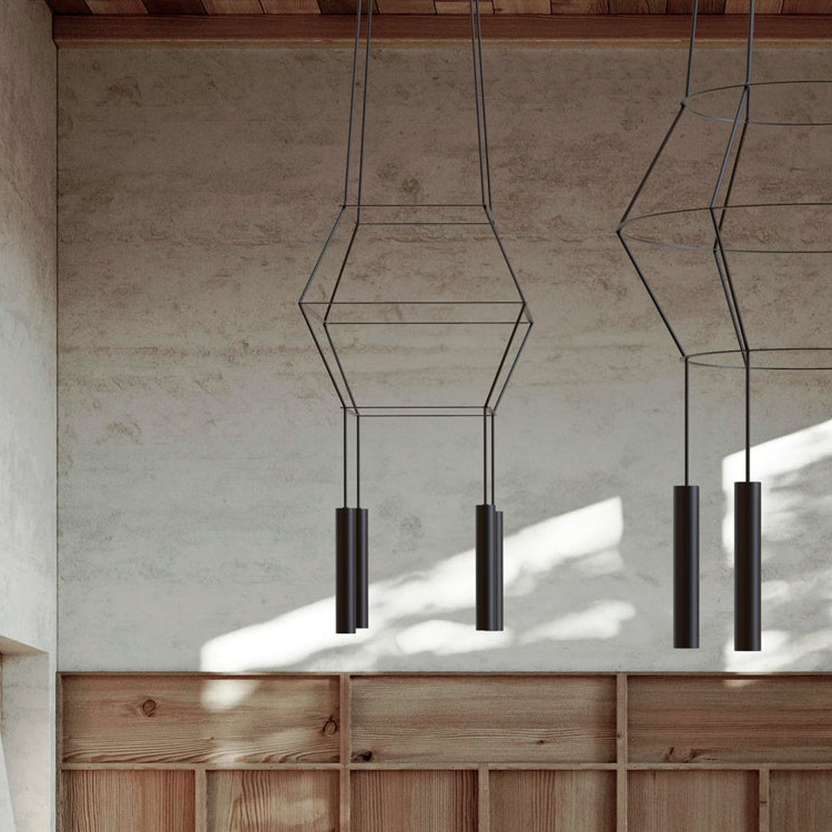 Rose Square 4 Light Cluster Chandelier in matt black, with stacked square wire frames and four cylindrical GU10 shades, shown hanging in a room with concrete walls and wood panelling.