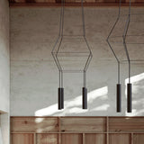 Rose Square 4 Light Cluster Chandelier in matt black, with stacked square wire frames and four cylindrical GU10 shades, shown hanging in a room with concrete walls and wood panelling.