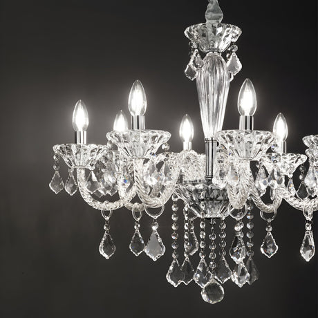 A close-up of the elegant Nimble Crystal 8 Light Chandelier in chrome, featuring eight lit bulbs, showcases its intricate hand-blown glass and multiple hanging crystal pendants. Set against a dark background, it creates a luxurious and sophisticated atmosphere.