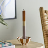 Dip Dye Fluted Candle in brown, cream, and mauve bands, displayed in a striped ceramic candle holder on a wooden side table in a living room setting.