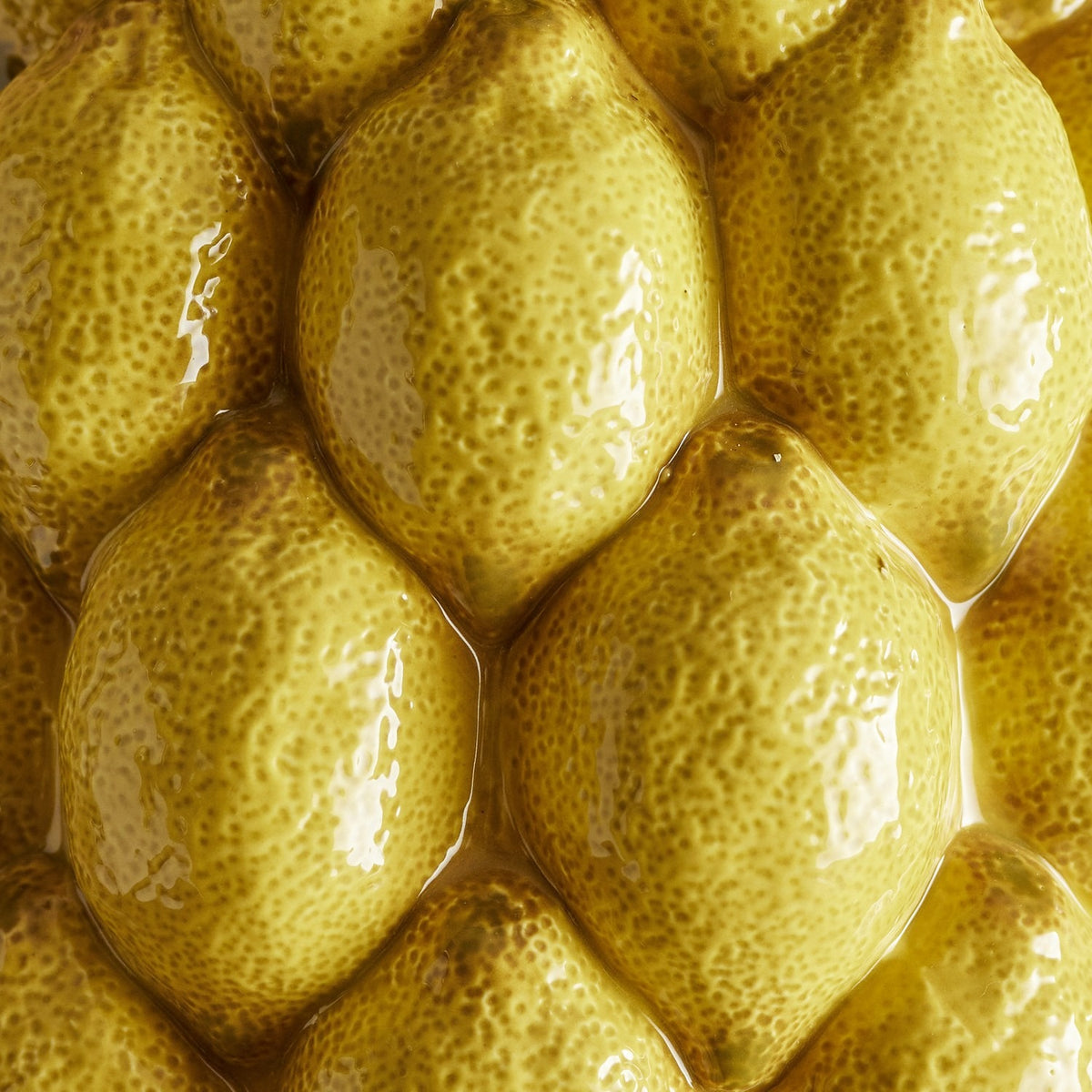 Close-up of the Limone Stoneware Vase 22cm in yellow, showing glossy raised lemon forms with dimpled, speckled ceramic texture covering the surface.