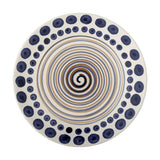 Shama Dotted Stoneware Dinner Plate in multicoloured ceramic, wide white rim with navy dot ring, centre painted with a blue and tan spiral, on a plain white background.