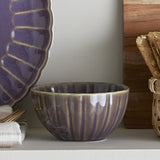 Latina Stoneware Bowl 9cm in grey with fluted ribbed sides, shown on a shelf beside a purple scalloped plate and crackers.