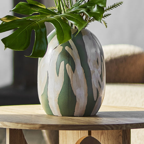 Adalena Stoneware Vase 30.5cm in green with a brushed hand-print motif in cream, holding green foliage on a wooden table in a living room setting.