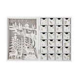 Elimar Wooden Advent Calendar in white, open book-style design with a cut-out winter forest and reindeer scene on one side and 24 numbered gold-detailed drawers on the other.