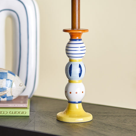 Kairi Stoneware Candle Holder 23cm in Multi, a striped, oval, and dotted ceramic column in blue, white and orange on a yellow flared base.