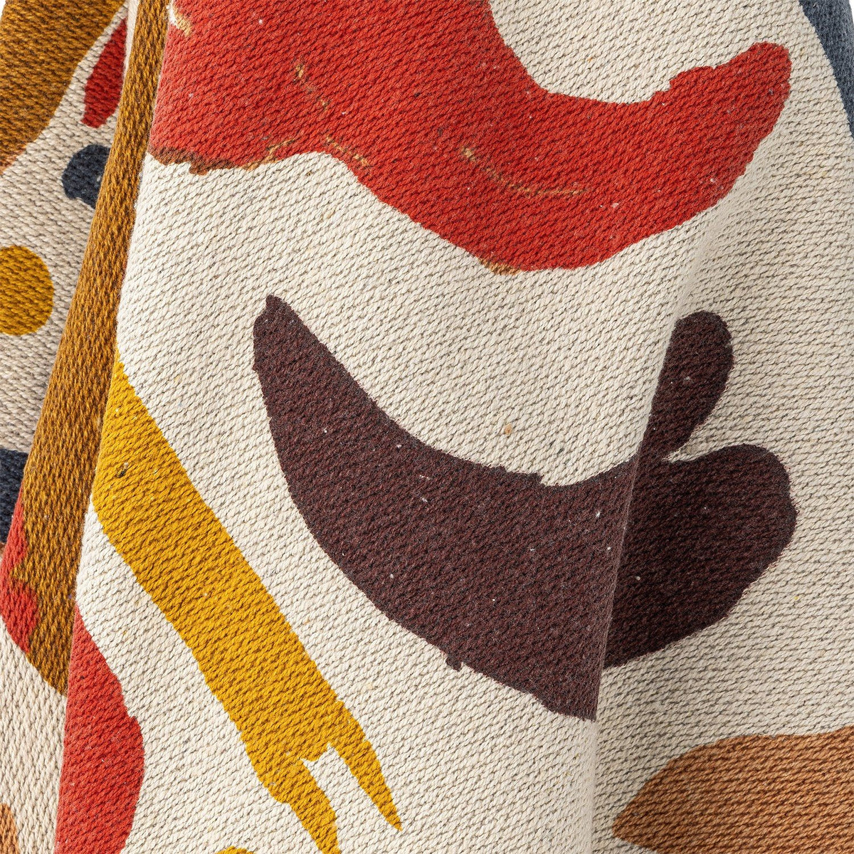 Close-up of the Horus Cotton Throw in multicoloured abstract pattern, showing bold brushstroke shapes in red, brown, mustard and navy on a woven cotton-blend fabric.