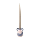 Ryker Stoneware Candle Holder in pink and blue with a two-handled vase shape and painted striped cat design, holding a tall taper candle against a white background.