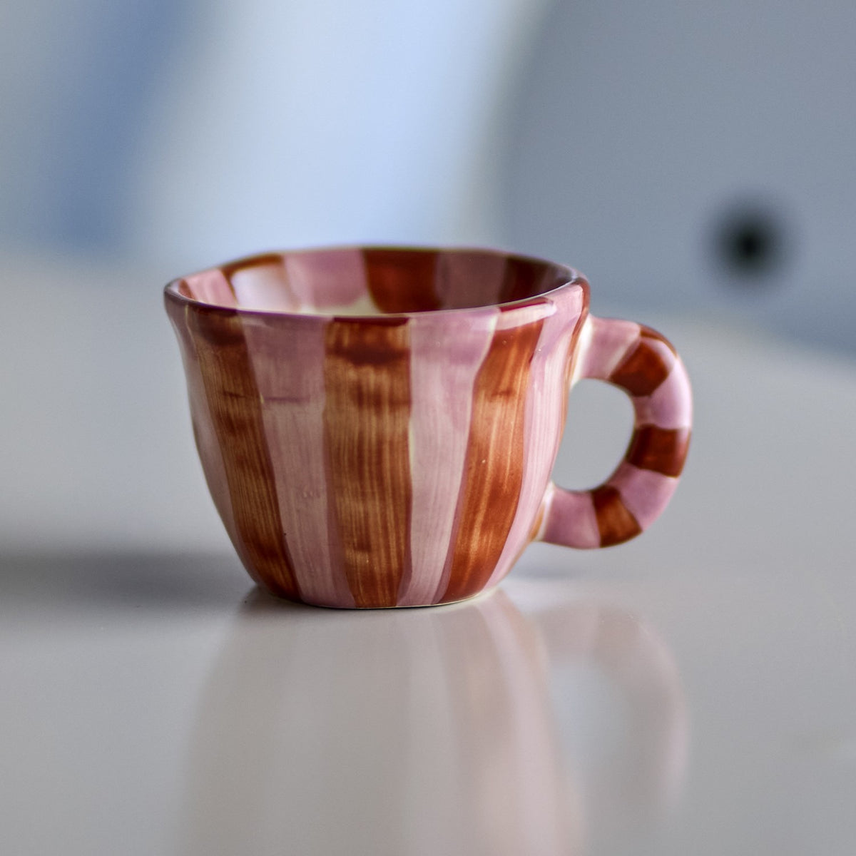 Nini Brown Striped Stoneware Cup 110ml, small ceramic espresso cup with hand-painted pink and brown vertical stripes and a chunky striped loop handle, shown on a light surface.