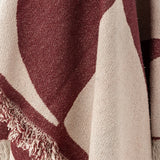 Close-up of the Olica Cotton Throw in red, showing woven texture with large curved cream shapes and a loose fringed edge.