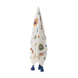Sylvie Cotton Throw in Multi, a kids' cotton-blend blanket printed with abstract jug-like faces, dots and squiggles, finished with navy tassels, hanging against a plain white background.
