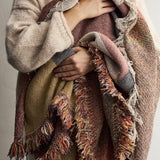 Arni Throw in Multi draped over the arm, showing the woven fabric with curved colour-block panels in rust, mustard and pink, finished with a long mixed-yarn fringe.
