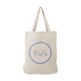 Celebrate Cotton Tote Bag in beige with twin handles, scattered confetti print, and a scalloped roundel logo on the front, shown on a plain white background.