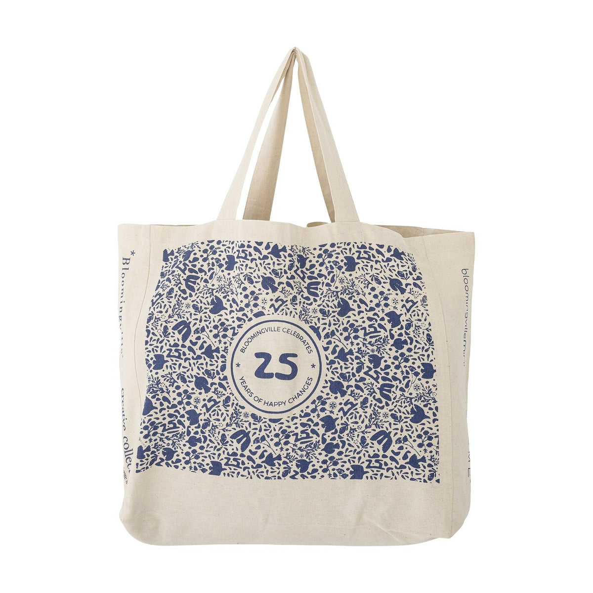 Beige cotton shopping bag with twin handles, printed with small blue motifs around a round 25 anniversary emblem and side lettering, shown on a white background.