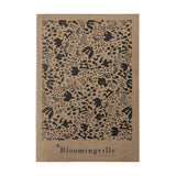 Anniversary Notebook in brown with a dense printed pattern of birds, flowers, and abstract shapes, "Bloomingville" text on the plain lower band, shown on a white background.