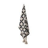 Forma Striped Throw in beige, hanging with an interlocking oval lattice pattern and tasselled corners, shown against a plain white background.